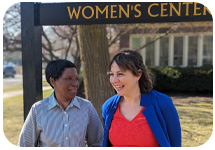 Njoki Kamau and Sarah Brown outside laughing standing in front of a sign that says "Women's Center"