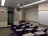 Picture of the classroom with purple chairs and whiteboard