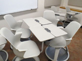4 white chairs with tables attached to the arm