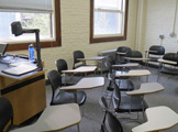 Photo of Locy Hall room number 109 showing a desk and some chairs