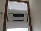 Photo of Locy Hall room number 110 showing air conditioner on the wall