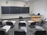 Photo of Locy Hall room number 111 showing two blackboards and some chairs