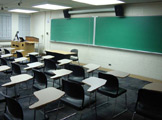View of classroom seats, podium, and blackboard at front of room.