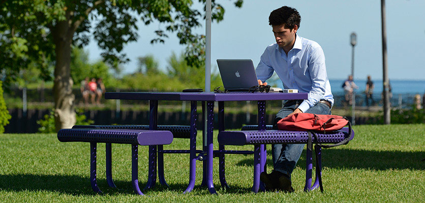 Student sitting outside of Norris working on his laptop