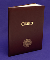 Image of Northwestern's charter. A brown book with gold lettering sitting upright.