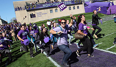 Undergrads running onto the field at halftime during a football game.