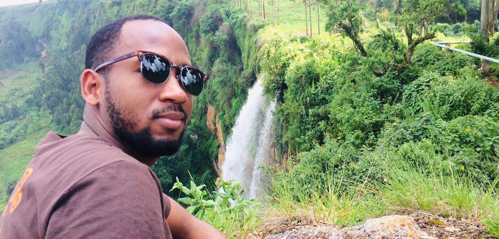 Student in front of the lush landscape of Uganda 