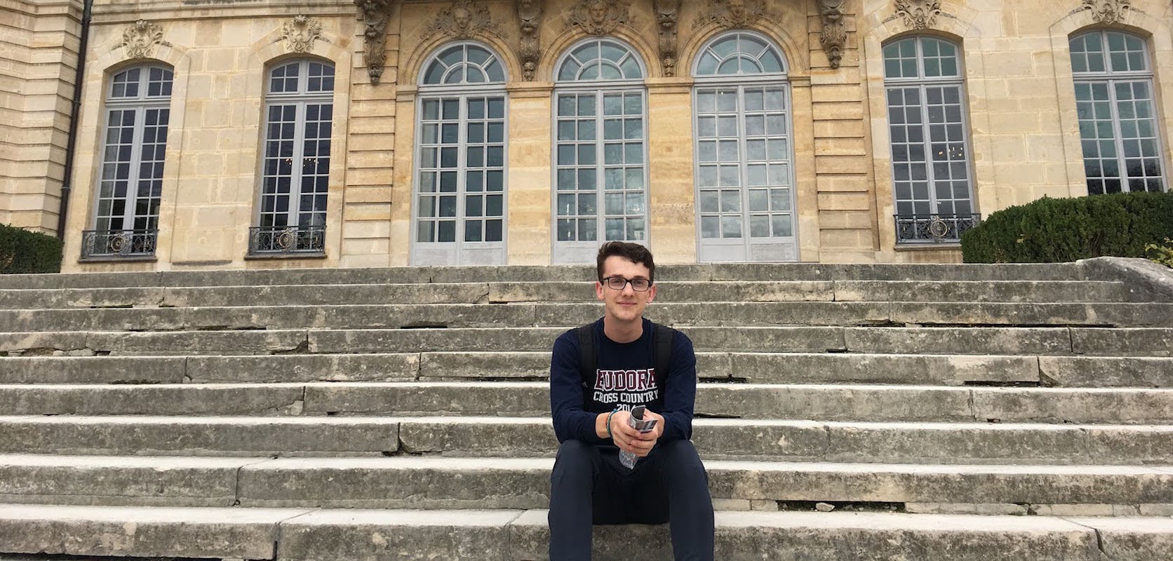 Student sitting on the steps in front of a museum in Paris, France