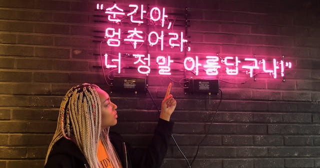 Student reading neon sign in cafe in South Korea
