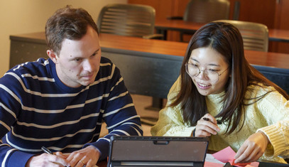 two students smiling with computer