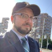 Michael Bugajski wearing a baseball capp and glasses, looking at the camera