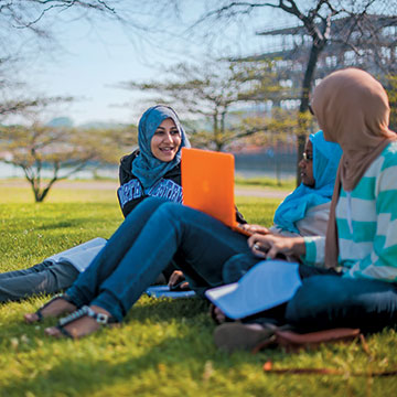 students sitting on the grass on campus