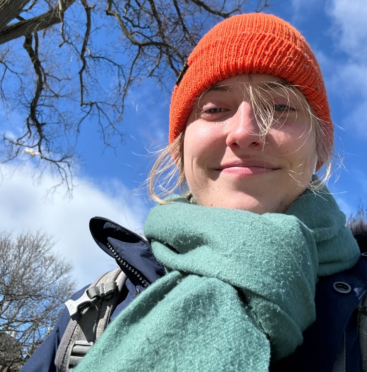 Cessa Lewis wearing an orange winter hat and green scarf standing outside