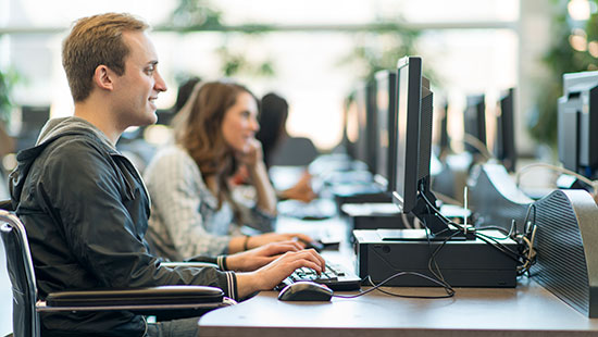 man in wheelchair sitting at computer desk