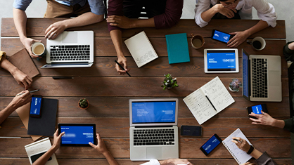 Aerial view of people working at table with laptops and paper.