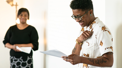 A person smiling looking down at paper.