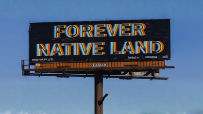 Billboard featuring words "Forever Native Land" among a clear blue sky.