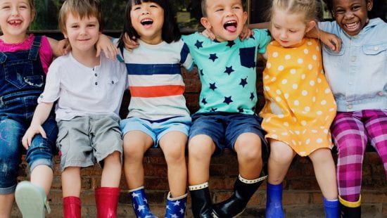 children smiling and sitting together arm in arm