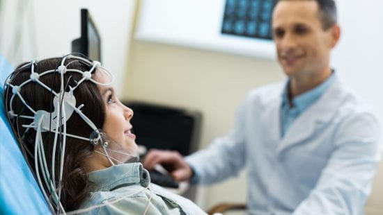 child with wires on head and doctor sitting beside them