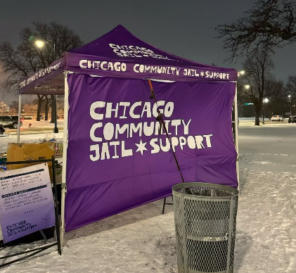 Purple Tent outside a night with snow on the ground, with the words " Chicago Community Jail Support" on the side