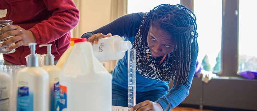 Image of a student pouring liquid in a beaker.