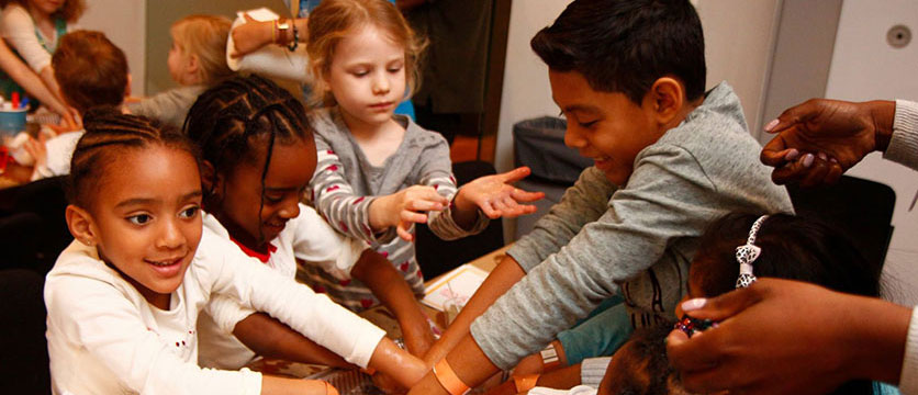 Image of children washing their hands in sudsy water.