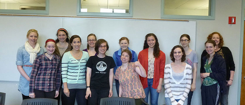 Image of a student group posing in a classroom in front of a whiteboard.