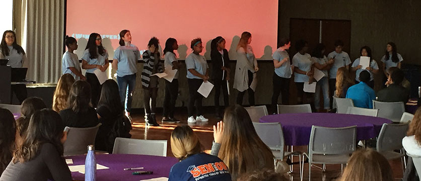 Image of a student group giving a presentation on a stage.