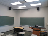 View of blackboards, podium and wall-mounted speakers.