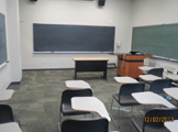 View facing front of classroom, including blackboard and podium.