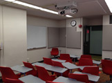 Image of classroom with red chairs that have attached desks