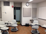 Picture of the room, chairs, white board, and wall clock