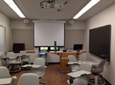 Picture of the front of the room with disorganized chairs, a screen and projector