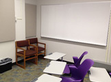 Picture of the side of the room with whiteboard and purple chairs