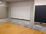 Picture of long table and chair and whiteboard on the wall
