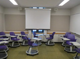 Picture of the front of the room with chairs and projector screen 