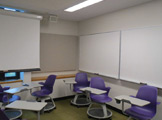 Picture of purple chairs and a white board on the wall