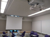 Picture of the front of the room with the projector screen showing