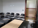 Photo of Locy Hall room number 110 shoiwng chairs and exit door