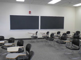 Photo of Locy Hall room number 111 showing two blackboards and a different arrangement of chairs