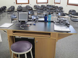 Photo of Locy Hall room number 111 showing teachers desk  and chairs