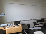 Photo of locy Hall Room Number 213 showing whiteboard and teachers desk
