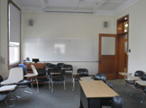 Photo of locy Hall Room Number 301 showing whiteboard and some chairs