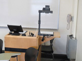 Photo of locy hall room number 305 showing podium and a phone on the wall