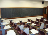View of chairs with built-in desks and blackboard.