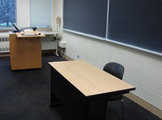 Podium, blackboard, and table in front of the room.
