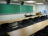 Blackboard and rows of tables with chairs. 