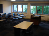 View of classroom seats, overhead projector and table in the front of the room.
