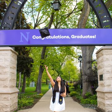 student at the arch throwing cap into the air
