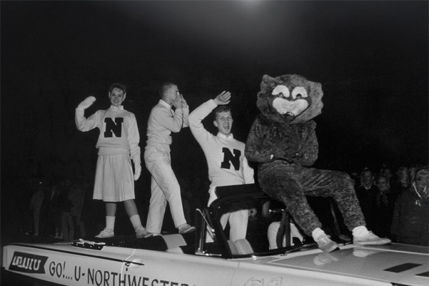 Willie and cheerleaders riding in a convertible